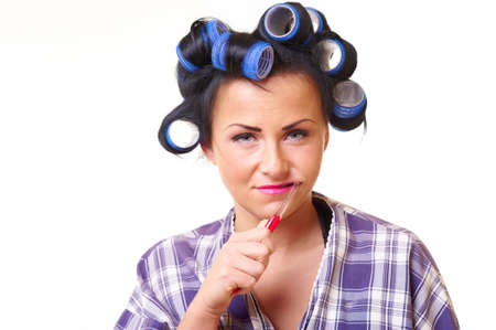 Displease housewife in bathrobe with tooth brush and curlersの写真素材