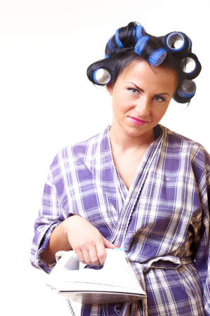 Displeased housewife with iron and curlersの写真素材