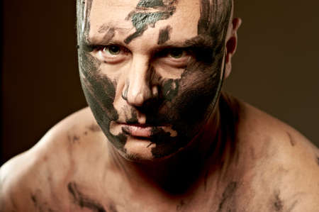 Emotional portrait of fighter. War paint on his face and body