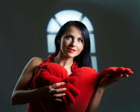 Artistic portrait of beautiful young brunette with heart in hands, St. Valentine conceptの写真素材