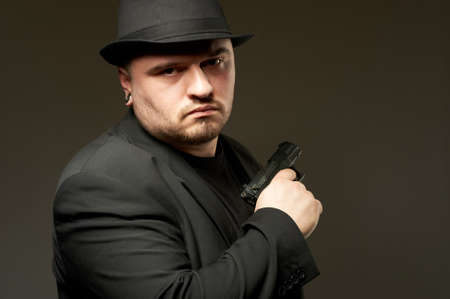Dangerous man in black suite and hat with gun.の写真素材
