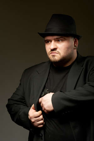 Dangerous man in black suite and hat with gun.