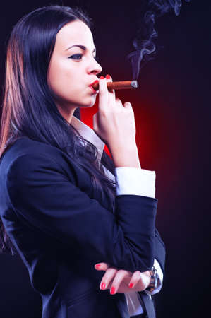 Beautiful elegant young woman with cigar, studio shotの写真素材