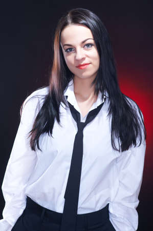 Elegant young woman in white mens shirt with black necktie, studio shotの写真素材