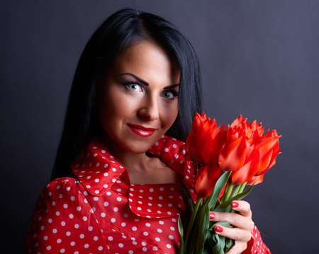 Portrait of a young woman in red gown with red flowers in handsの写真素材