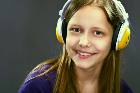 Closeup portrait of a smiling teen girl with headphones, studio shotの写真素材