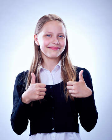 Portrait of a smiling teen girl showing thumbs up, studio shotの写真素材