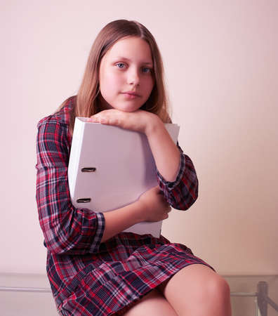Portrait of a school girl with folder, studio shotの写真素材