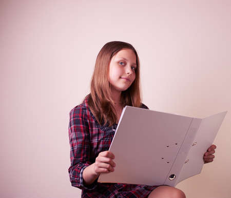 Portrait of a school girl with folder, studio shotの写真素材