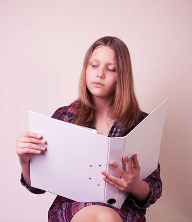 Portrait of a school girl with folder, studio shotの写真素材