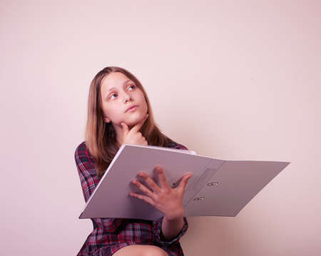 Portrait of a school girl with folder, studio shotの写真素材