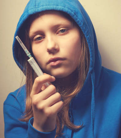 Dark portrait of a junk teen girl with syringe, problems with drugsの写真素材