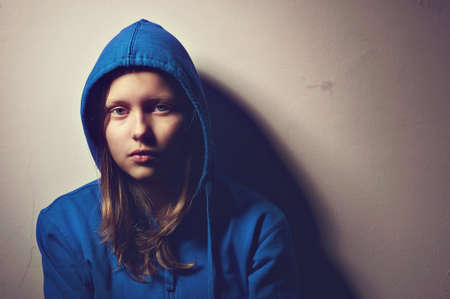 Sad teen girl in hood sittingの写真素材