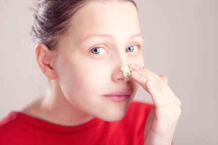 Happy teen girl with scrub mack on her face having fun and making funny facesの写真素材