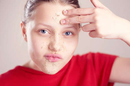 Happy teen girl with scrub mack on her face having fun and making funny facesの写真素材