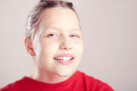 Happy teen girl with scrub mack on her face having fun and making funny facesの写真素材