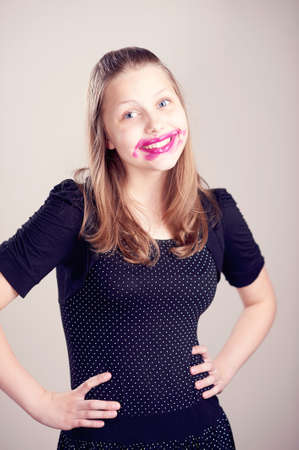 Happy teen girl posing with pomade on lips and cheeks