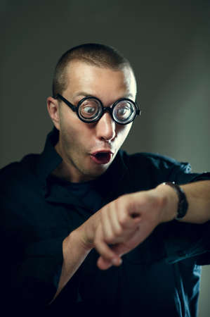 Nerd guy in glasses looking at watches and surprisingの写真素材