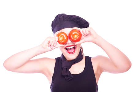 Cute happy teen girl in chef hat with tomatoes having funの写真素材