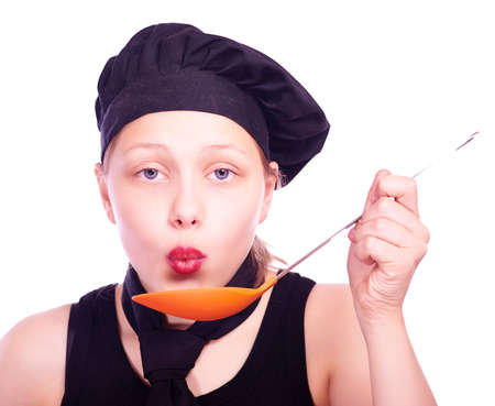 Cute happy teen girl dressed in chef hat taste something from ladleの写真素材