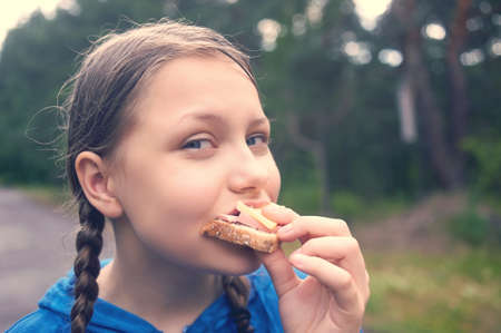 Happy teen girl walking in the forest in the rain and eating