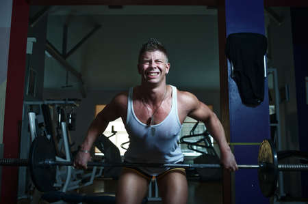 Portrait of a strong guy doing exercises with barbellの写真素材