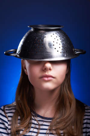 Calm teen girl with a colander on her headの写真素材