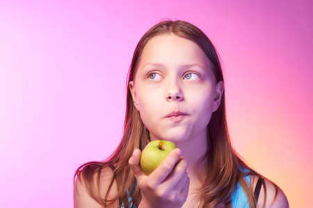 Portrait of an emotional funny teen girl eating appleの写真素材