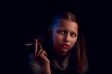 Teen girl from a dysfunctional family sits and smokesの写真素材