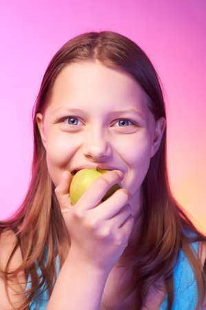 Portrait of an emotional funny teen girl eating appleの写真素材