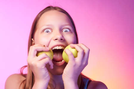 Portrait of an emotional funny teen girl eating appleの写真素材