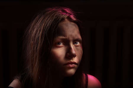 Dirty frightened teenage girl sits locked in a dark roomの写真素材