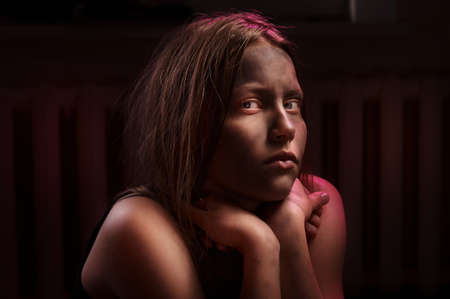 Dirty frightened teenage girl sits locked in a dark roomの写真素材