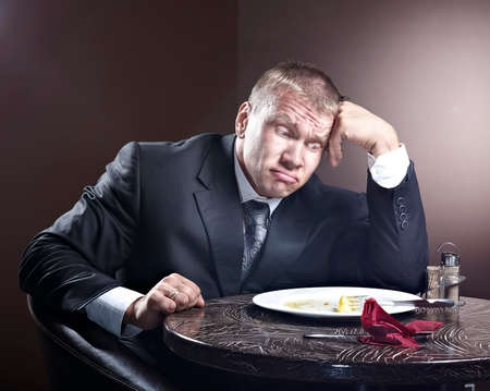 Muscular businessman eating and lick the plateの写真素材