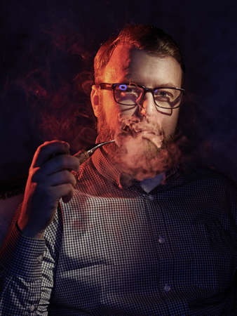 Elegant man smokes a pipe. Studio shot.