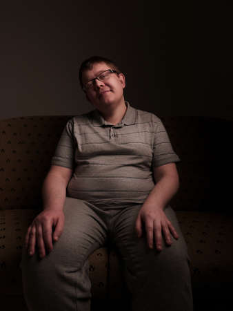 Lazy overweight male sitting on couch and watching somethingの写真素材