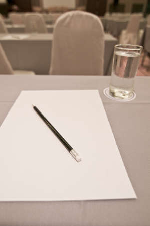 White paper with pencil and glasses on table in meeting room