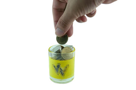 Male hand dropping a coin into a bankの写真素材