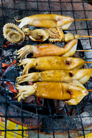 Squid Barbecue Raw Skewer Set on hot charcoal stove serve