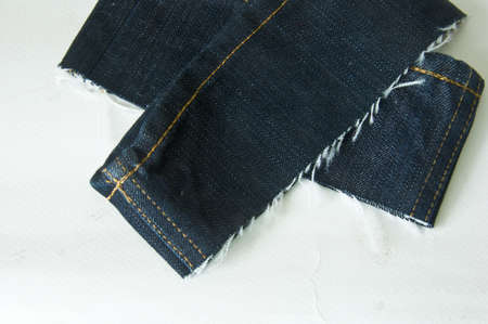 Edge of blue jeans fabric with fringe on whiteの写真素材