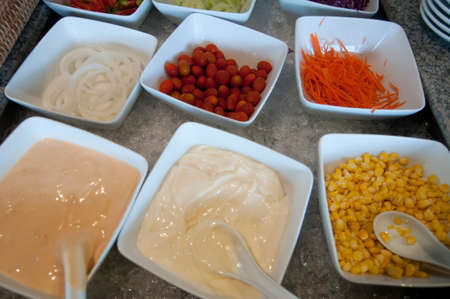 dressing and fresh vegetables on a salad barの写真素材