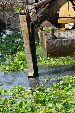 A canal boat with long pneumatic digging arm in canalの写真素材