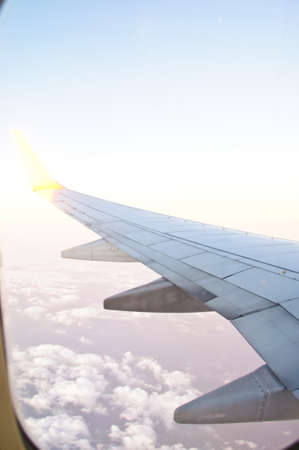 Wing of the plane lit by the sunset on a background of skyの写真素材
