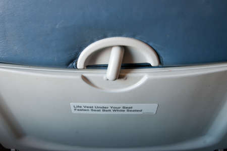 inside airplane seat, focusing with the warning label of "fasten seat belt"の写真素材