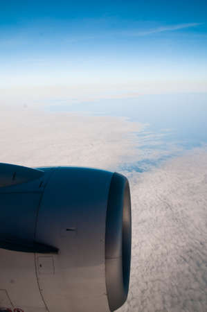 Airplane in the blue sky engine and wings white cloudsの写真素材