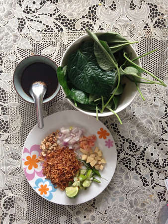 Miang Kham is a tasty snack often sold as Thailand street food  It involves wrapping little tidbits of several items in a leaf, along with a sweet-and-salty sauce  の素材