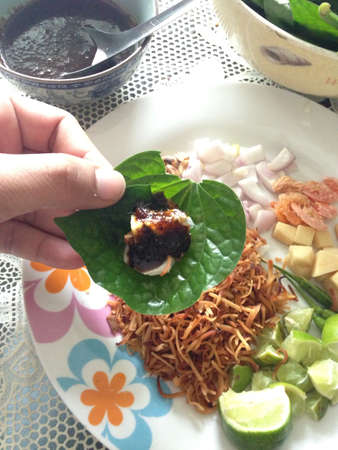 Miang Kham is a tasty snack often sold as Thailand street food  It involves wrapping little tidbits of several items in a leaf, along with a sweet-and-salty sauce  の素材