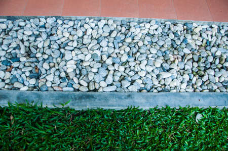 stones pebbles and green grass background decoration in gardenの写真素材
