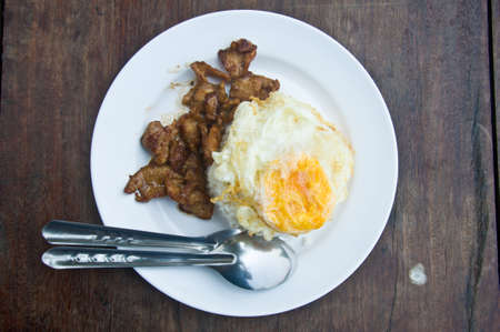 Pork fried garlic and fried egg on woodの写真素材