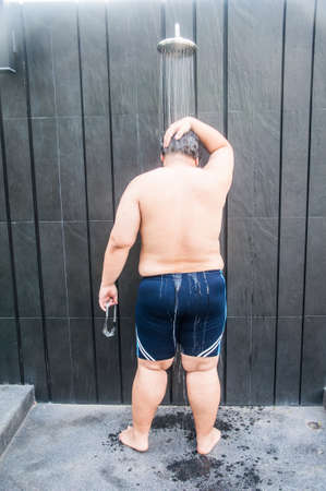 Fat man take shower after pool swimの写真素材